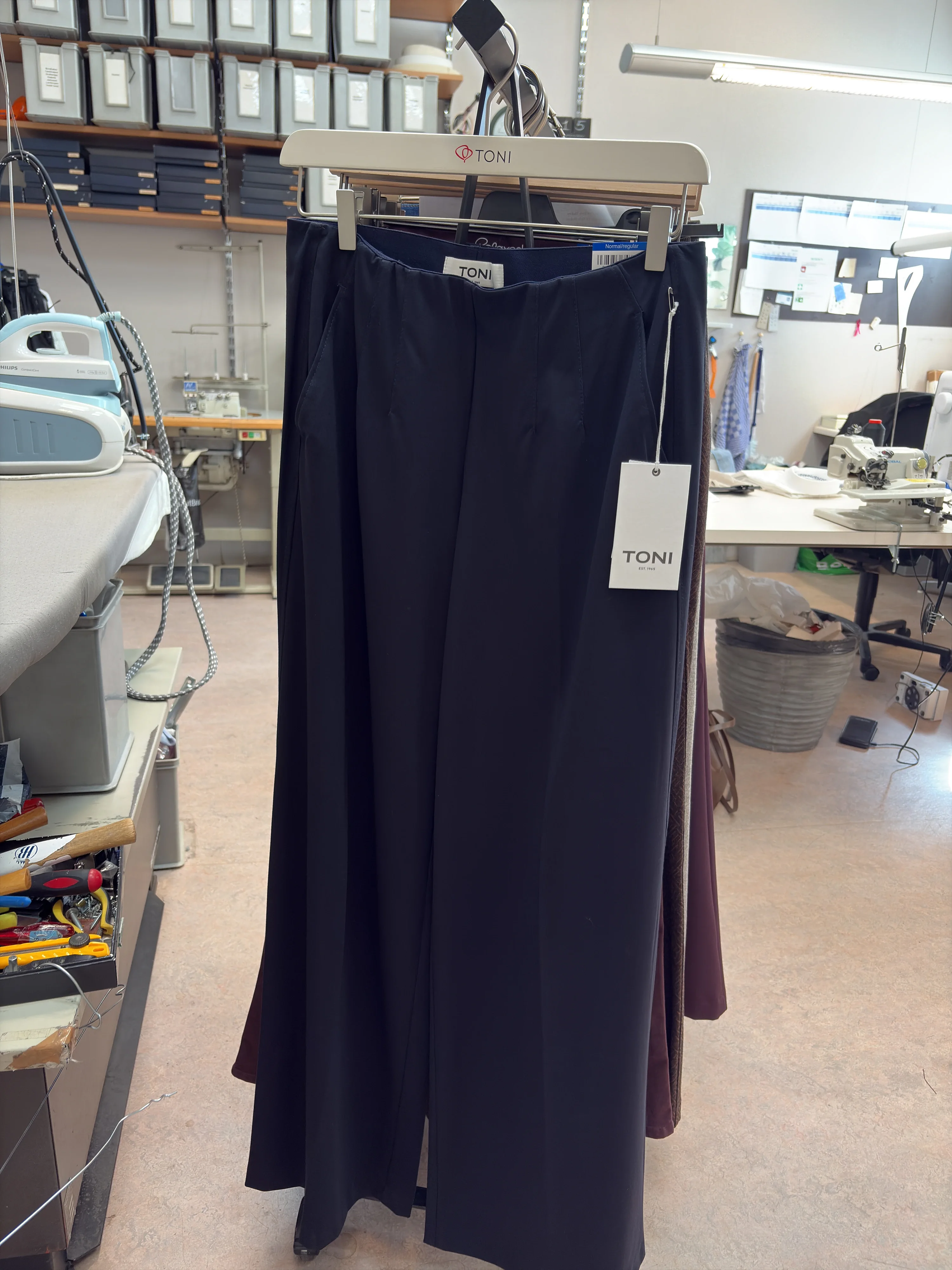 Marineblauwe pantalon aan een kledingrek in het atelier