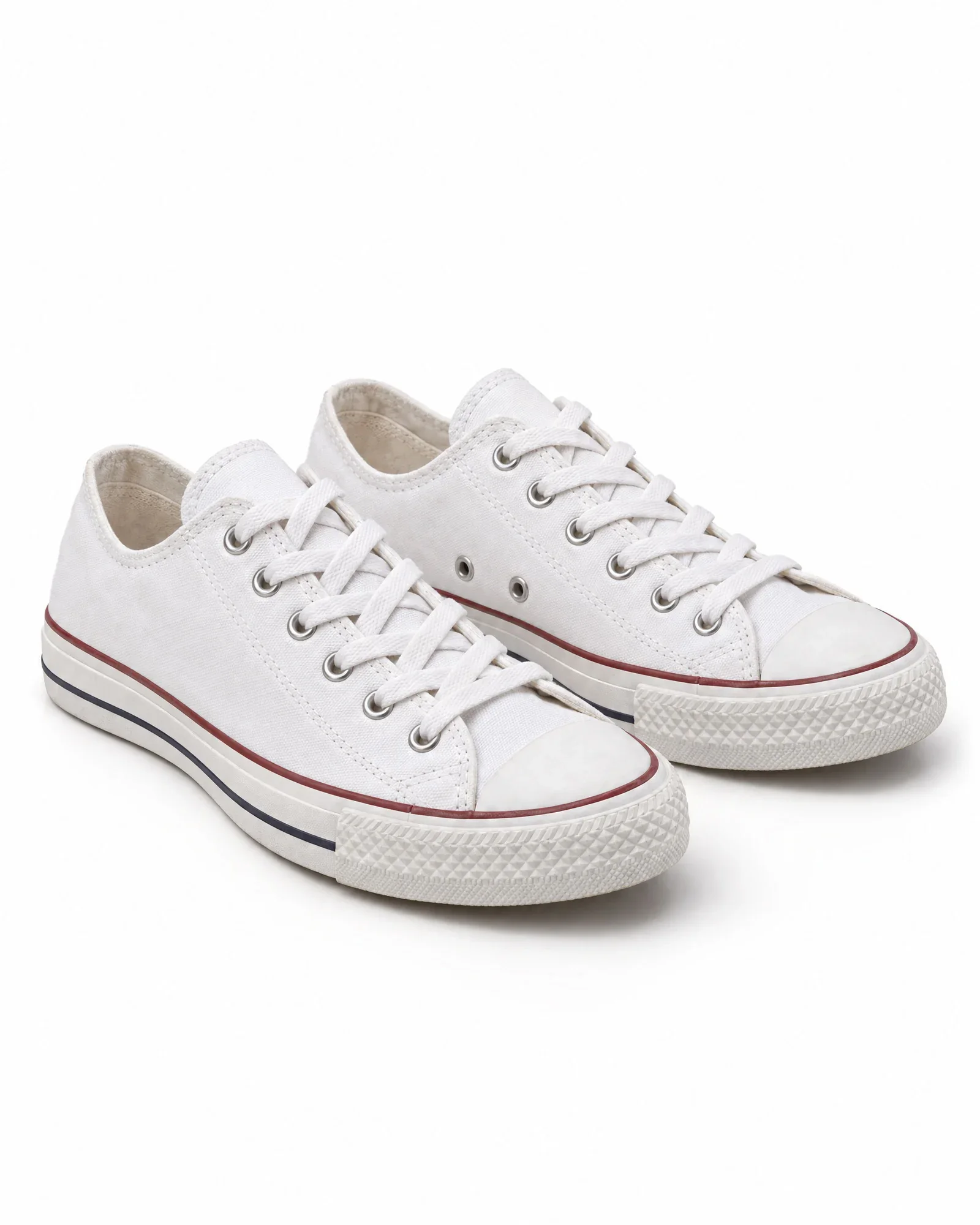 Paar witte canvas sneakers zonder logo, schuin van voren op een witte achtergrond