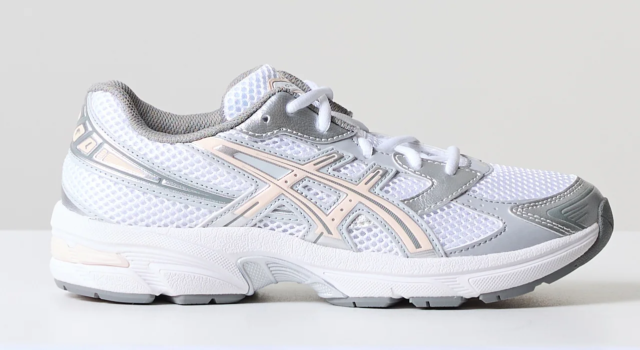 Eenvoudige foto van een witte sneaker op tafel tegen een grijze muur