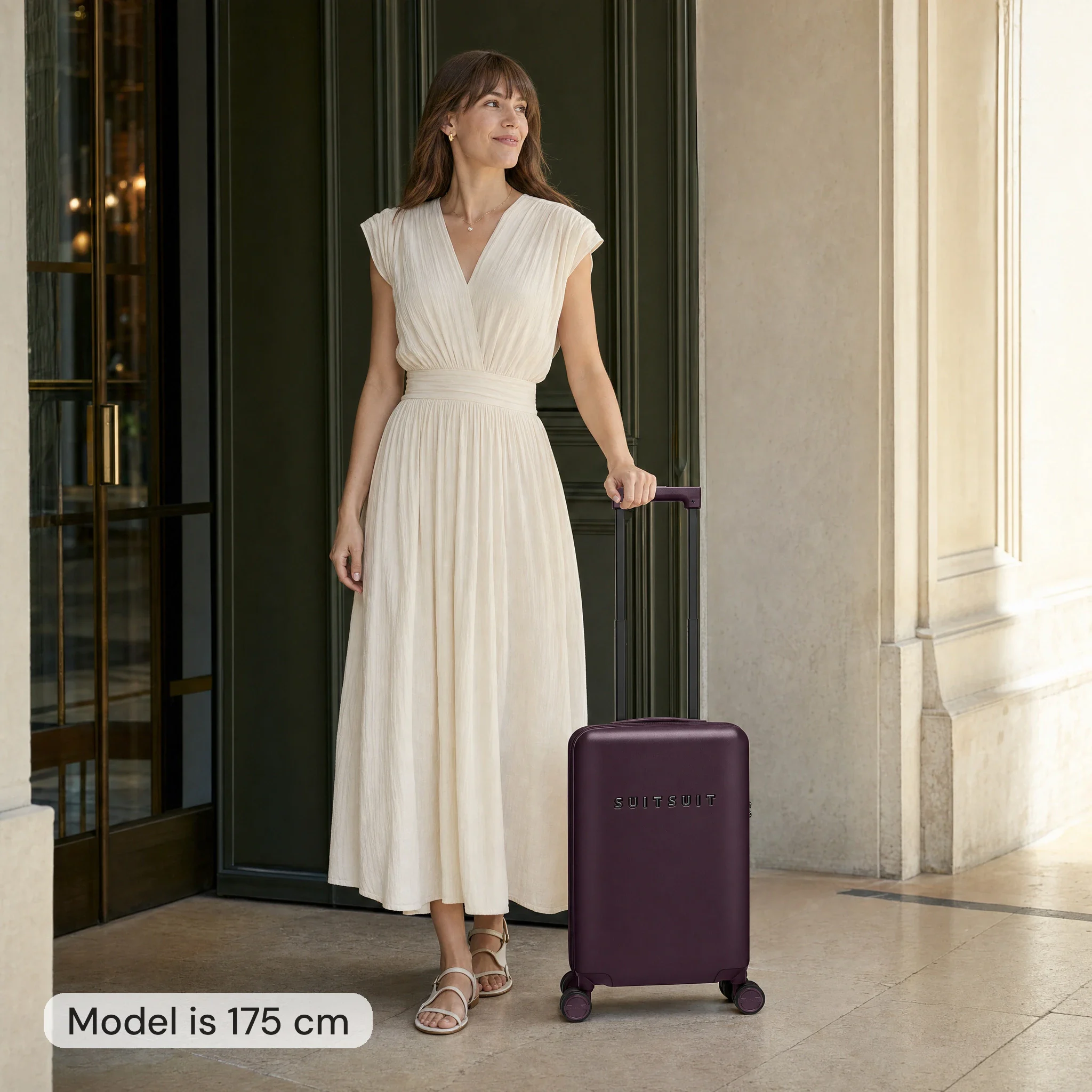 AI-modelbeeld: vrouw van 175 cm naast een bordeauxrode Suitsuit-handbagagekoffer van 54 cm hoog