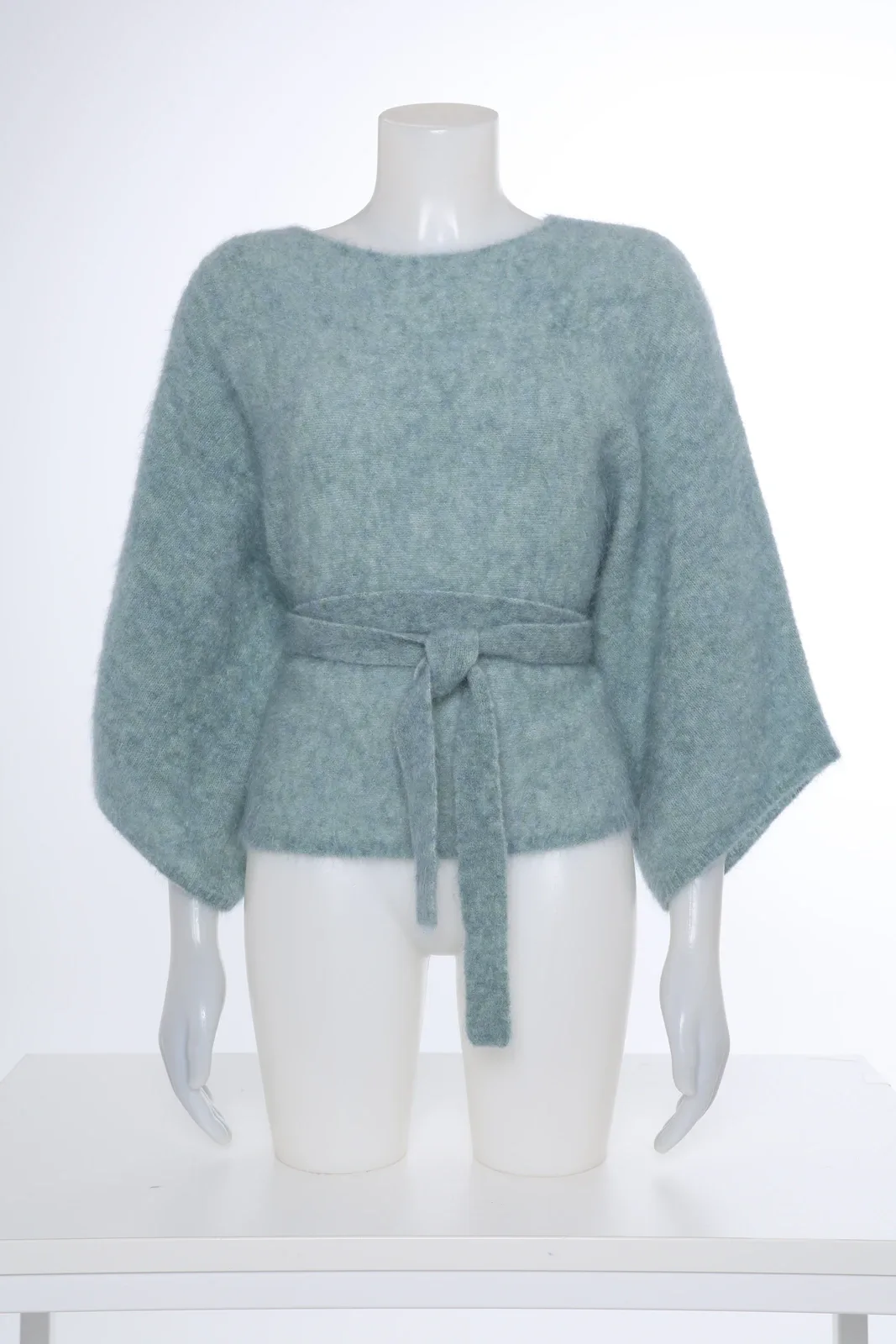 Mintgroene gebreide top met strikceintuur op een mannequin
