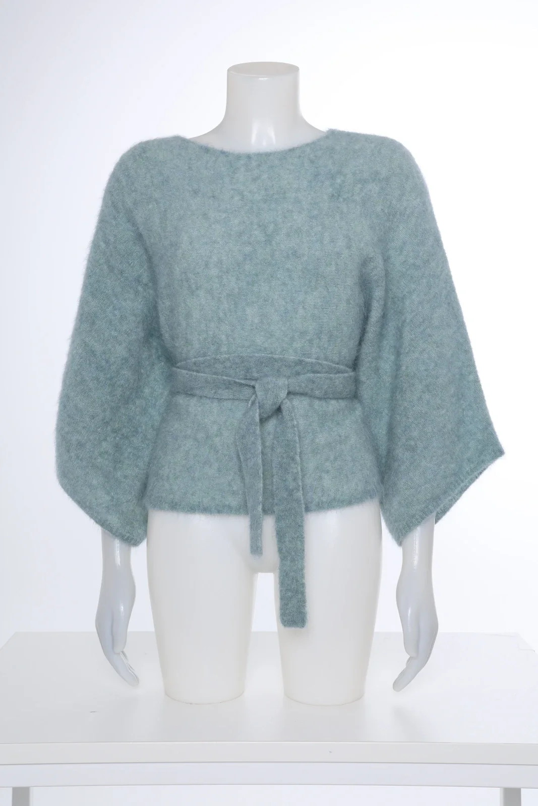 Mintgroene gebreide top met strikceintuur op een mannequin