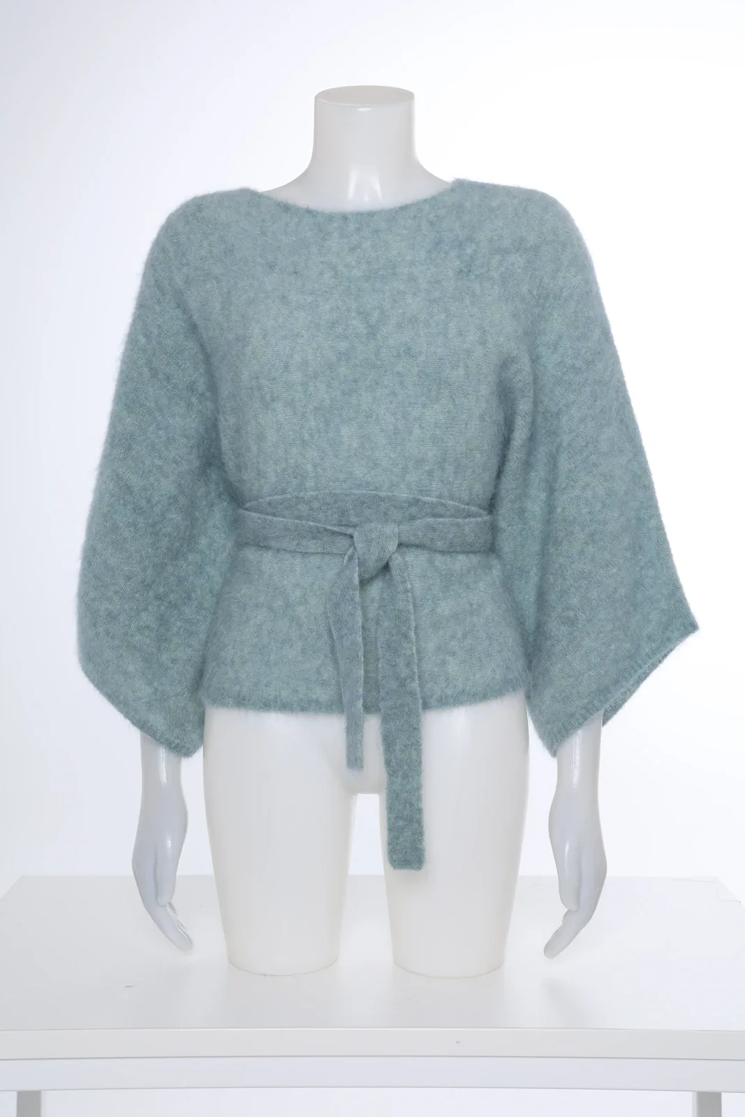 Mintgroene gebreide top met strikceintuur op een mannequin
